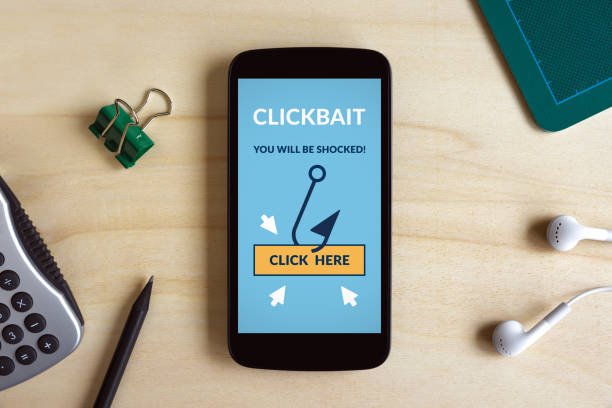 istock Clickbait concept on smart phone screen on wooden desk 1019547816