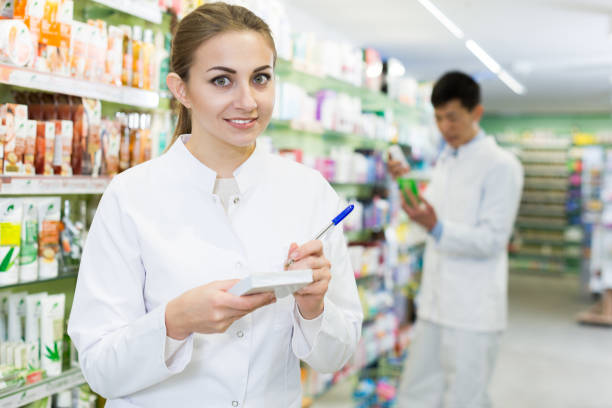 istock Female in uniform is  looking medicine with notebook  in pharmacy 1019548566