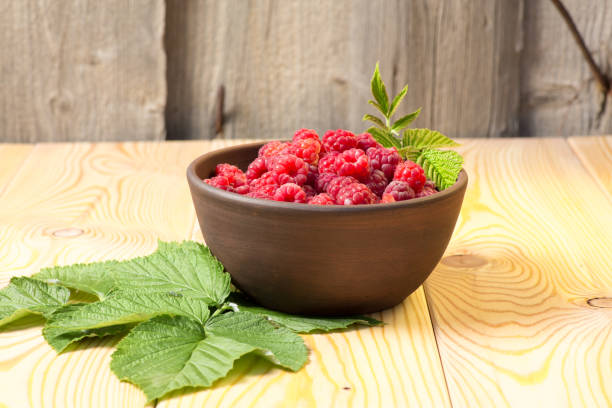istock Fresh organic healthy raspberry with mint leaves in clay dish on wooden table background. Rustic style and natural light. food photo. 1019554576
