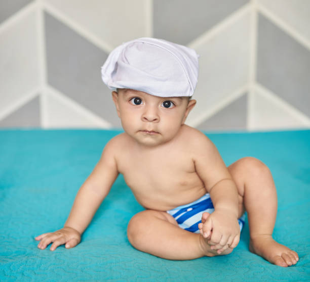Baby boy in cloth diaper sit on soft bed blanket
