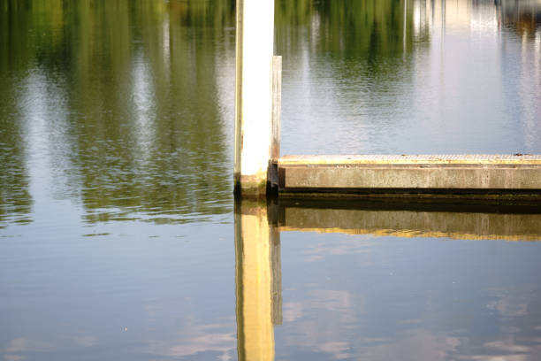 Steel pillars are reflected on a river bank in the water.
