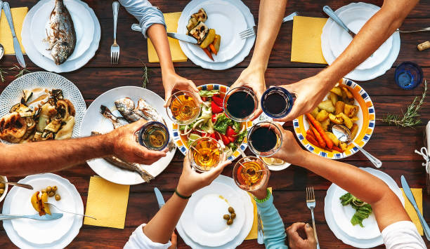 istock Big family dinner. Top view on served table and hands with clinking goblets 1019591608