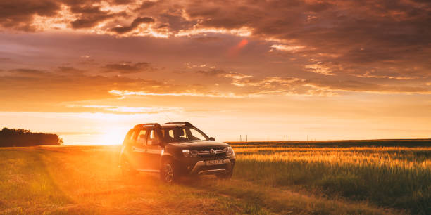 Renault Duster Or Dacia Duster Suv In Road Through Summer Wheat Field In Amazing Sunset Time. Duster Produced Jointly By French Manufacturer Renault Gomel, Belarus - June 22, 2018: Car Renault Duster Or Dacia Duster Suv In Road Through Summer Wheat Field In Amazing Sunset Time. Duster Produced Jointly By French Manufacturer Renault dirt road sunset stock pictures, royalty-free photos & images