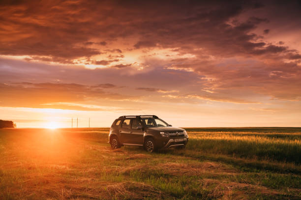 renault duster o dacia duster suv en carretera a través de campo de trigo de verano en tiempo de puesta de sol increíble. producido conjuntamente por el fabricante francés renault duster - dacia fotografías e imágenes de stock