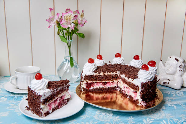 istock Chocolate cake with cream and cherry on the serving table. 1019615876