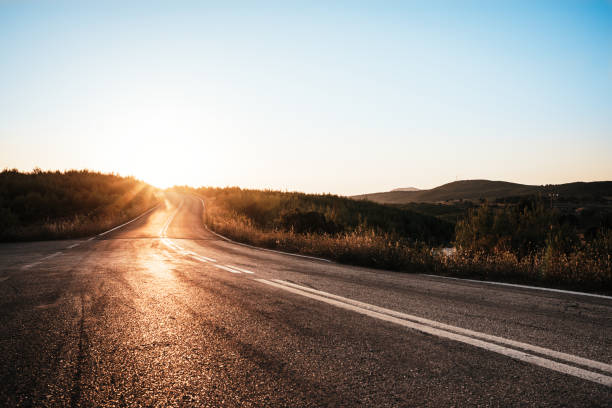 kurvenreiche straße zu strahlen des sonnenuntergangs - curve driving winding road landscape stock-fotos und bilder