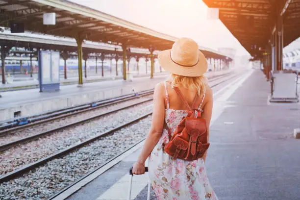 travel background, woman traveler with baggage, passenger waiting for the train on platform of railway station