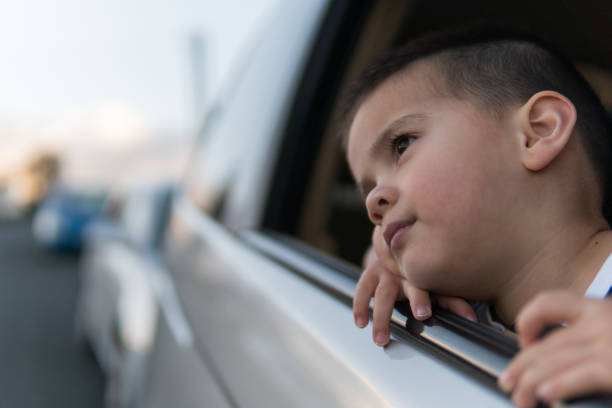 Little boy day-dreaming and looking out the car window stock photo