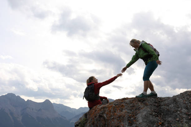istock Female climbers helping each other up a mountain 1019631992
