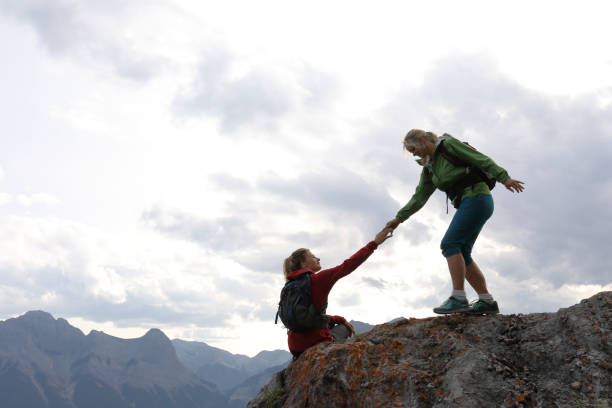 istock Female climbers helping each other up a mountain 1019634222