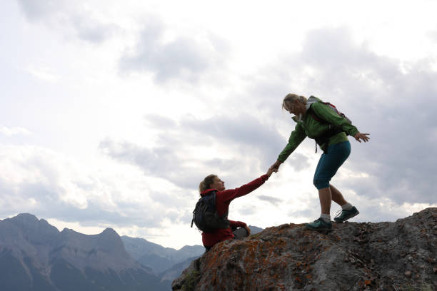 istock Female climbers helping each other up a mountain 1019634286