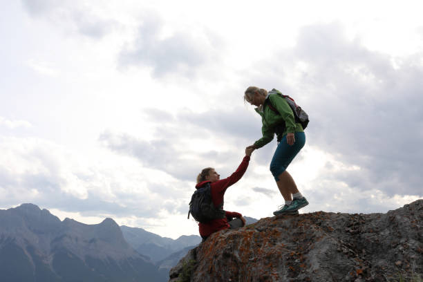 istock Female climbers helping each other up a mountain 1019634372