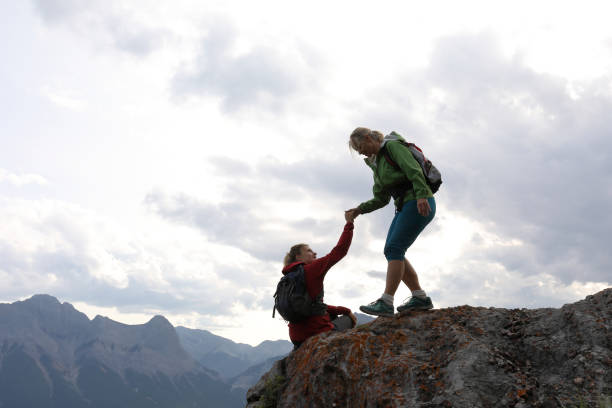 istock Female climbers helping each other up a mountain 1019634486