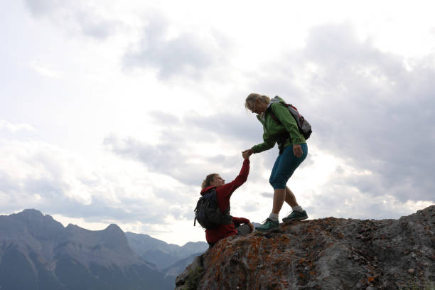 istock Female climbers helping each other up a mountain 1019634606