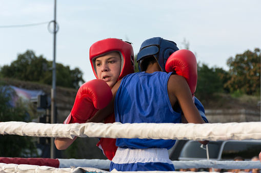Nis, Serbia - August 14, 2018: Outside in the city square in Niš city, the event is a boxing match. Two young mans boxing in ring outdoor. Fighters are in clinch. Sport match outdoor. Close up, selective focus. Shooting in city of Nis, Serbia, Europe