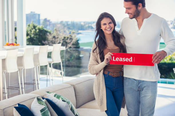 young couple holding a leased rental sign in a luxury home. - for rent sign house sign happiness imagens e fotografias de stock