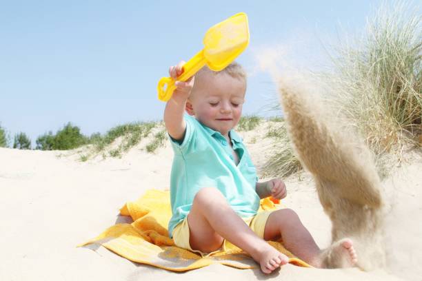 istock cute two year old little boy playing in sand at beach 1019659038