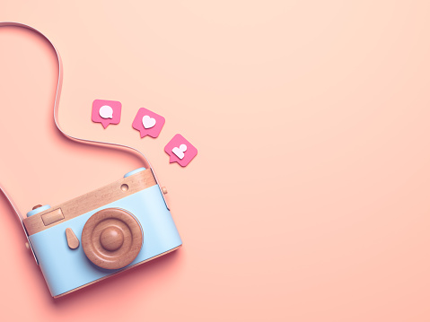 Vintage wooden photo camera with Pin heart, friends, comment, post. Overhead view of Traveler's accessories, Flat lay photography of Travel concept. Pink isolated background. 3d render