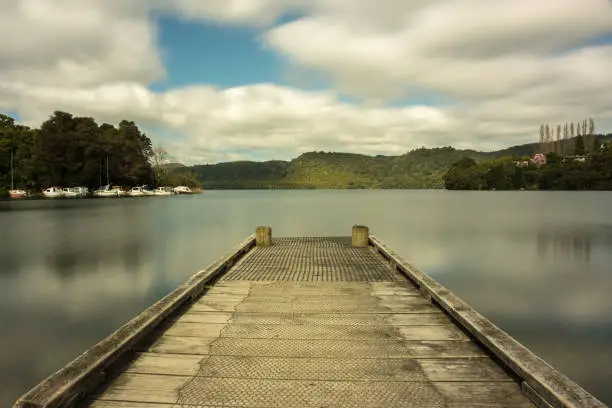 Photo of wooden pier at the lake surrounded by forest