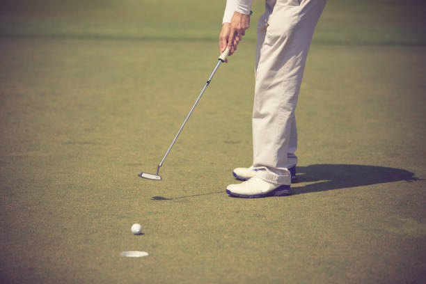 istock Golf player at the putting green hitting ball into a hole 1019701538