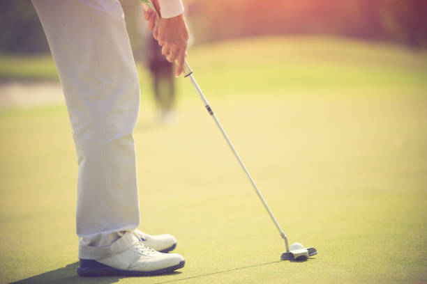 istock Golf player at the putting green hitting ball into a hole 1019701556