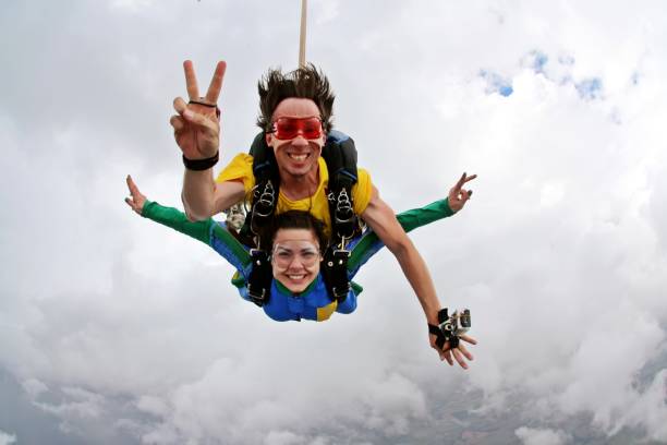 felicidad de tandem de paracaidismo en un día nublado - paracaídas fotografías e imágenes de stock