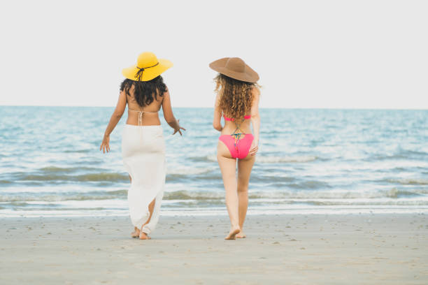 istock Happy women go sunbathing at sand beach in summer. 1019726942