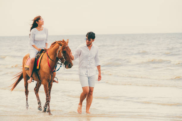 istock Young couple goes horse riding on tropical beach. 1019729182