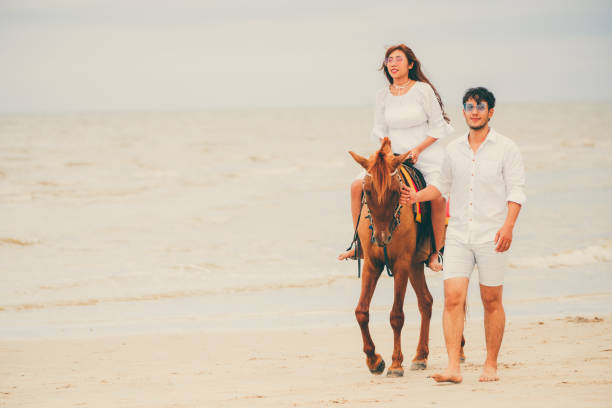 istock Young couple goes horse riding on tropical beach. 1019729184