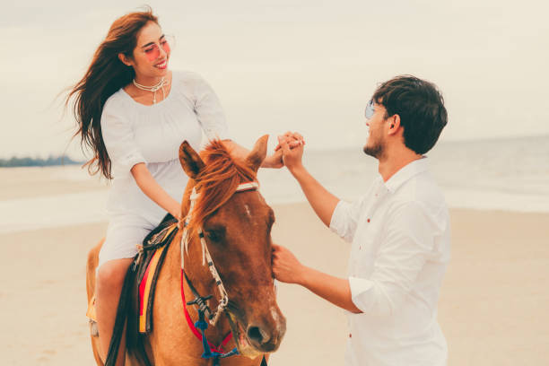 istock Young couple goes horse riding on tropical beach. 1019729204