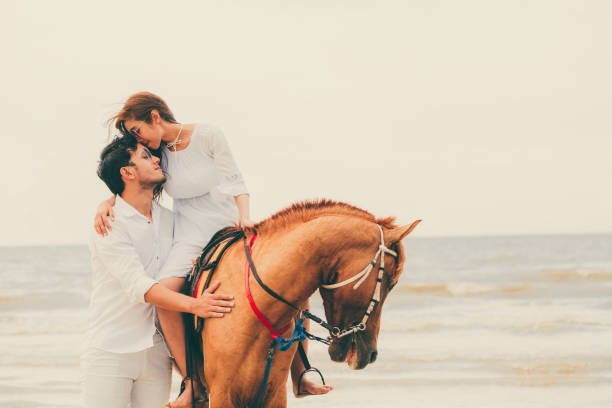 istock Young couple goes horse riding on tropical beach. 1019729238