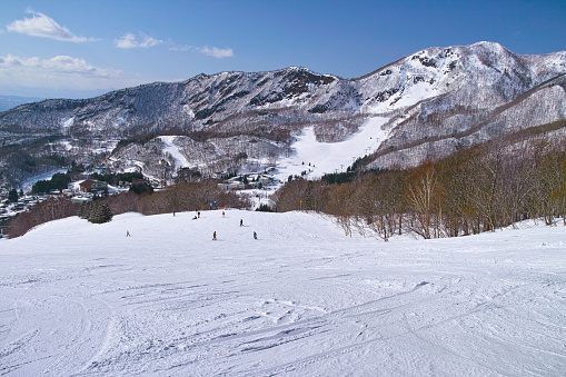 Yamagata, Japan - 7 March 2018: Scenery in the early March of Zao Onsen Ski Resort in Yamagata Prefecture of Japan. Skier sliding down the Sunrise course where you can see the spa town.