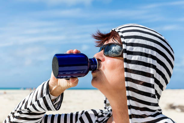 Senior woman drinking refreshing water from a bottle in desert