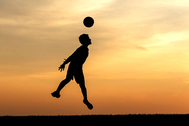 Full length portrait of boys posing with soccer ball in middle of road. Boy standing with his brother in their community. They are smiling and looking at camera.