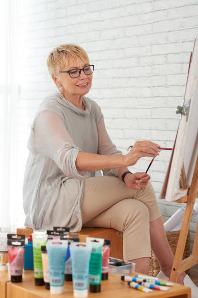 istock Cheerful old woman painting 1019799350