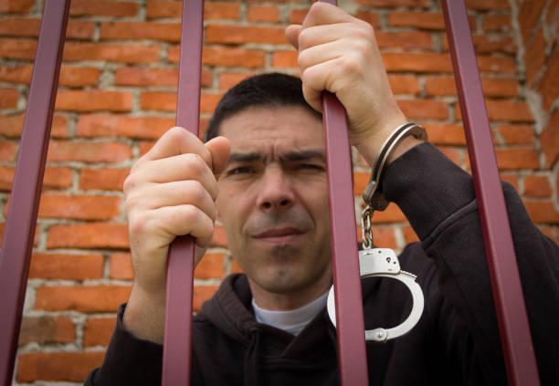 istock The prisoner behind the bars.Hold with hands on the grids 1019802574