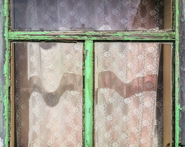 Old wooden window frame with peeling green paint, shades and shadows on a sunny day