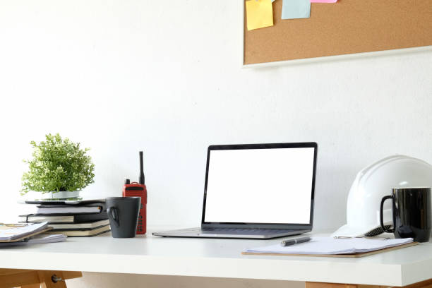 istock Engineer workspace with laptop and safety helmet on white table. 1019858232