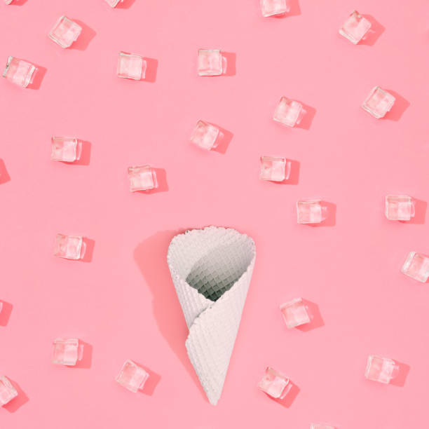 istock Ice cubes pattern with white ice cream cone on pastel pink background. 1019858850