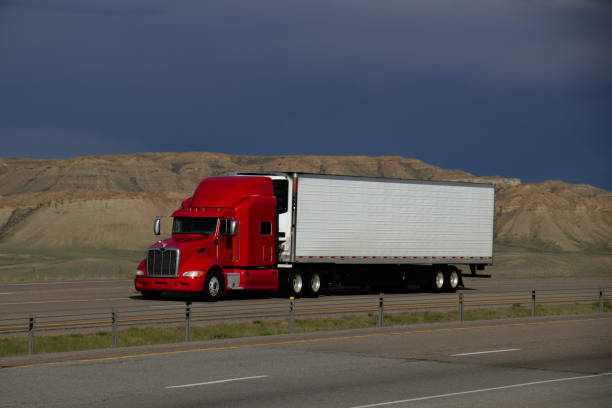 A Red Kenworth Semi-Truck pulls a blank white Trailer along a rural US Interstate.