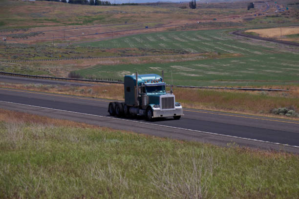 A high angle shot of a big tanker truck rolling down on a highway surrounded by green fields