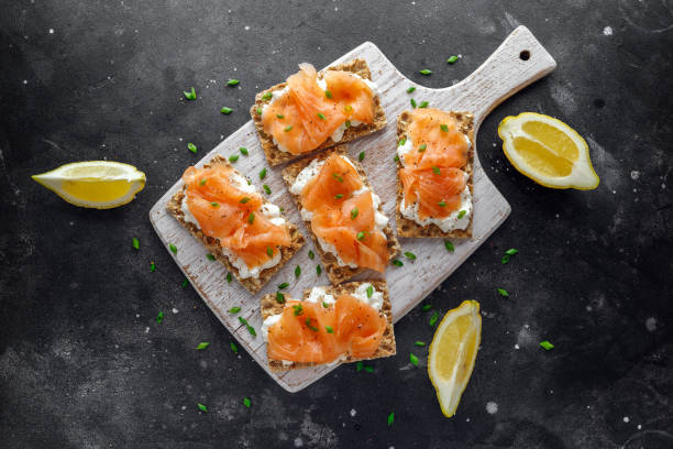 casero tostadas de centeno con salmón ahumado y queso suave, cebollino en pizarra - bruschetta buffet party food fotografías e imágenes de stock