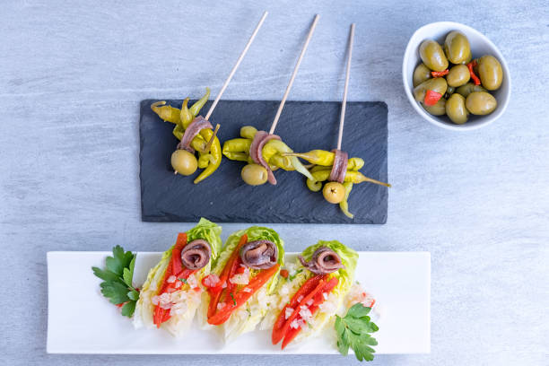 little gem lettuce with anchovies and peppers, traditional appetizer , named 'gilda', olives, cider.  basque country cuisine. spain - salad food and drink food lettuce imagens e fotografias de stock
