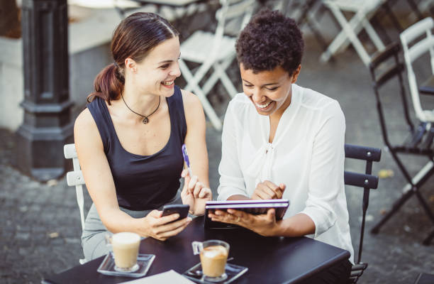 istock Two Young Businesswomen at a Sidewalk Cafe 1019913248