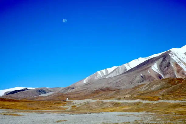 Crystal clean blue sky with morning moon. Snow mountains and highlands between Xinjiang and Pakistan. Peaceful landscape, love nature, very mindfulness.