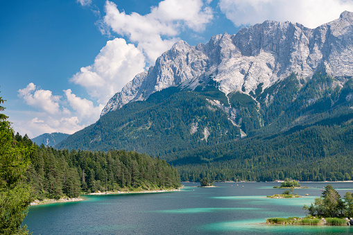 The beautiful Lake Eibsee at the foot of the famous and highest Mountain Zugspitze in Bavaria, Southern Germany. Lots of tourists enjoying this perfect summer day on the lake. Converted from RAW.