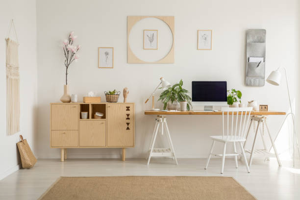 istock Wooden cupboard next to desk with desktop computer in home office interior with posters. Real photo 1019950928