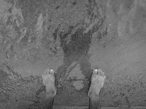 Reflection of the sky and unrecognizable tourists on the seashore.