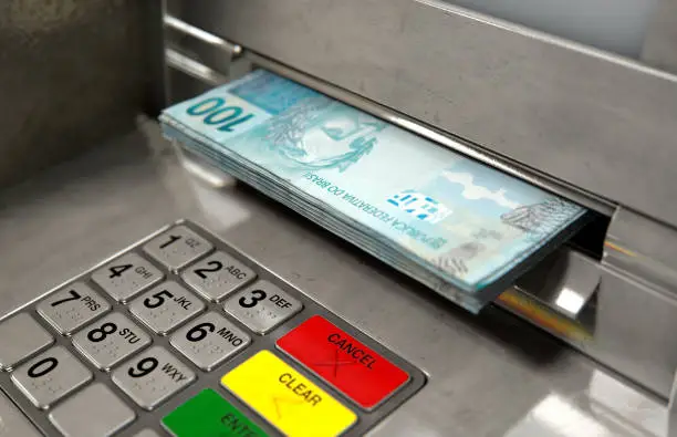 A closeup view of an atm facade with an illuminated sceen and keypad and a wad of brazilian real banknotes being withdrawn from the cash slot - 3D render
