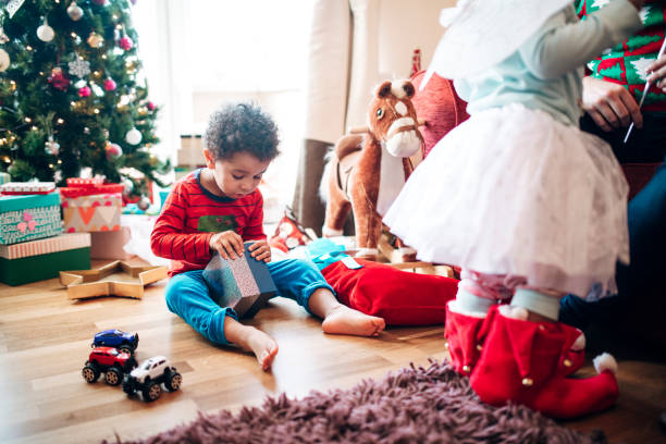 jongetje opening van een gift in christmas time - engelenpak stockfoto's en -beelden